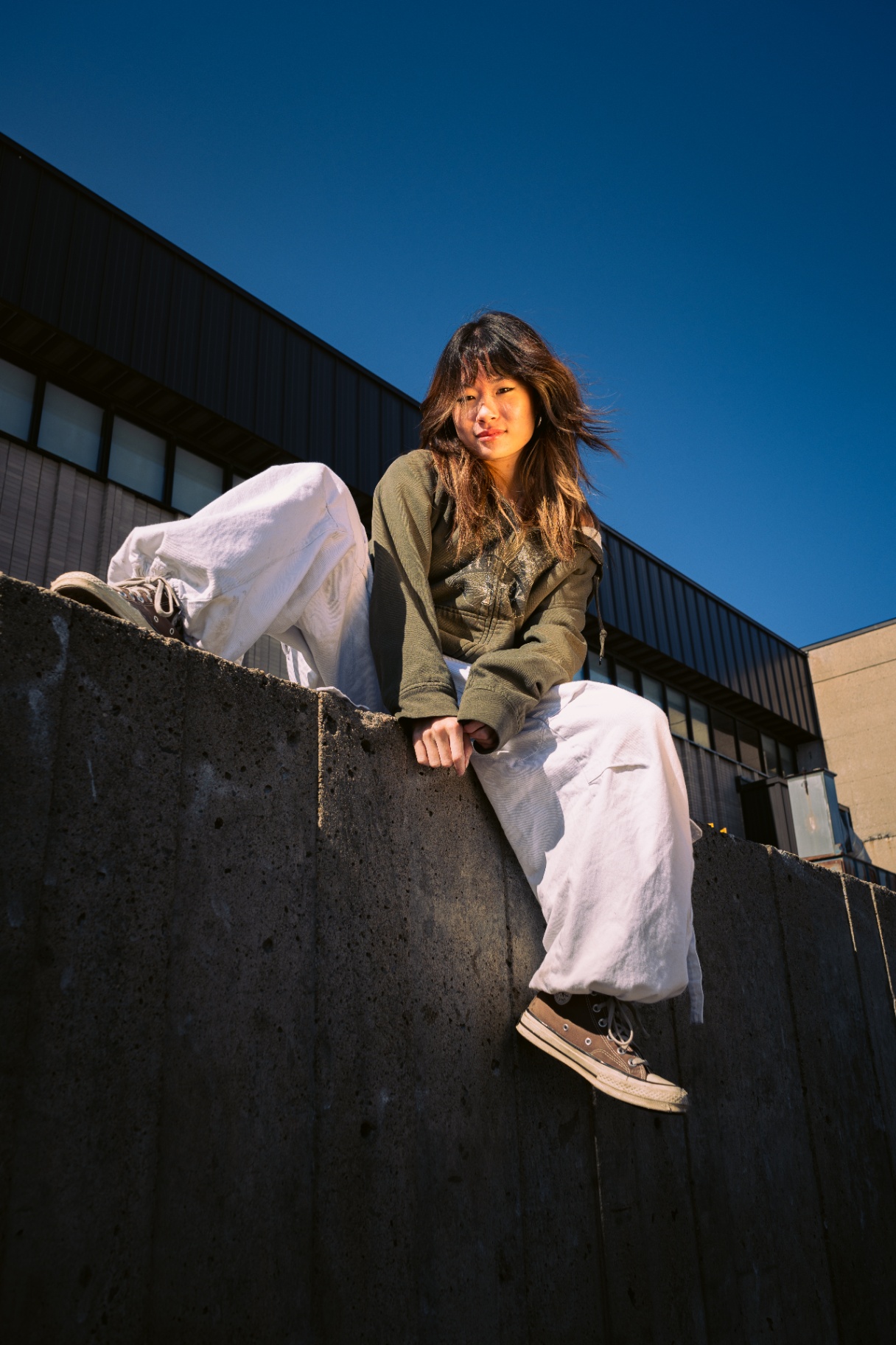 Dancer against a concrete wall under blue sky.